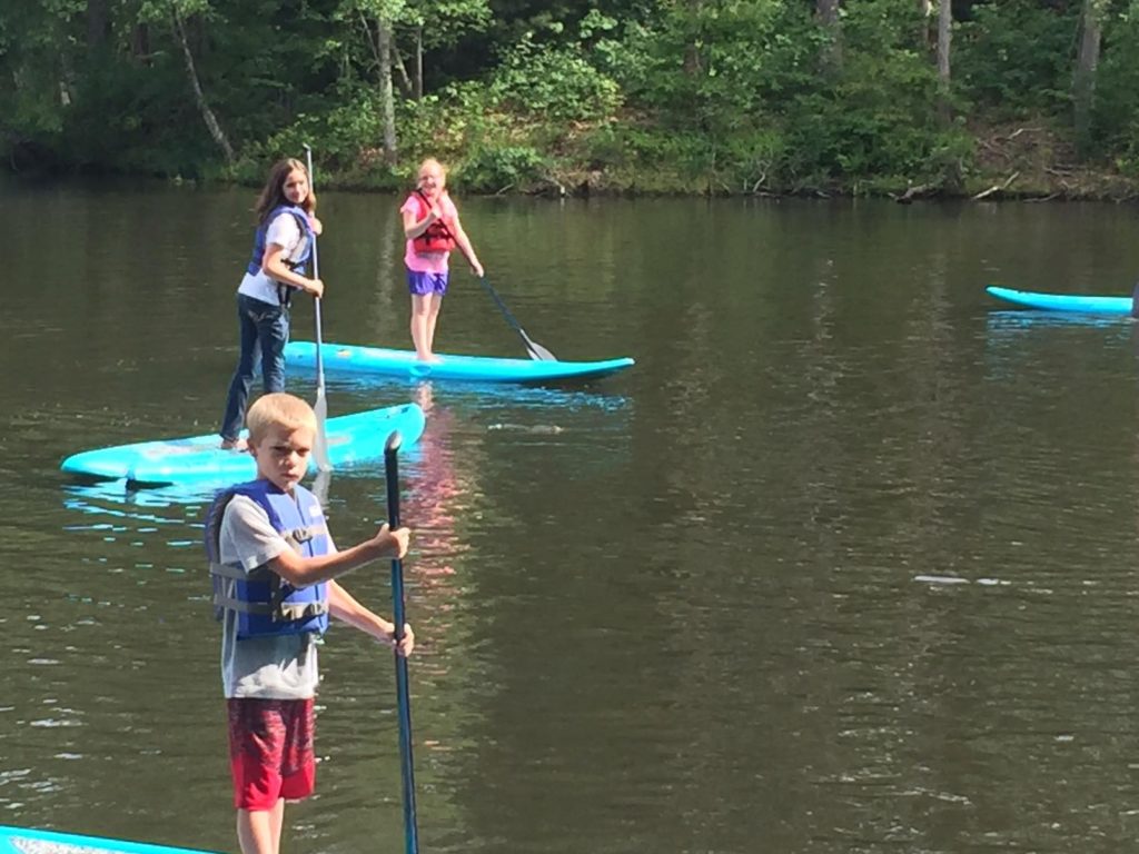 Campers paddleboarding on the lake