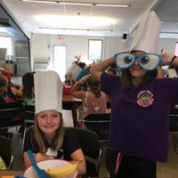 Campers wearing funny paper hats and novelty glasses