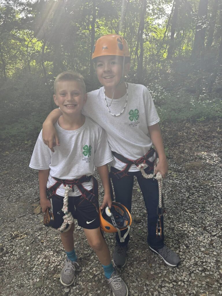 2 kids smiling dressed in zipline gear
